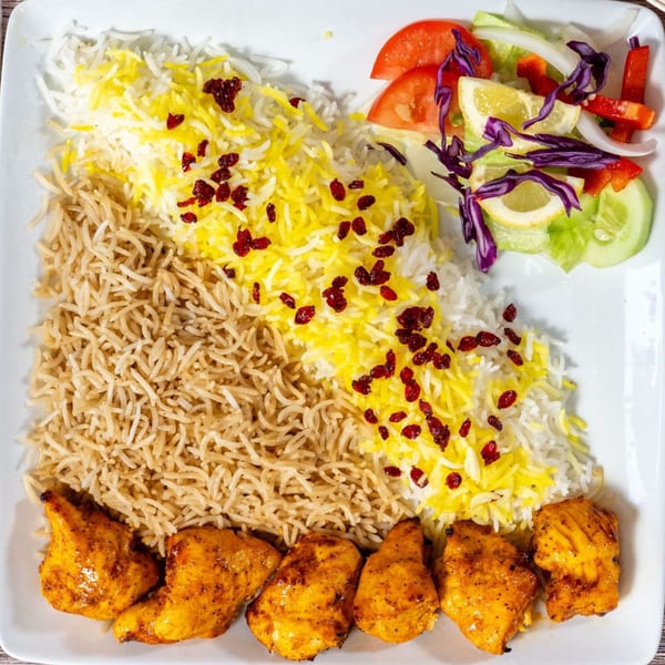 Chicken kabob with two types of rice, topped with barberries, and a side salad.